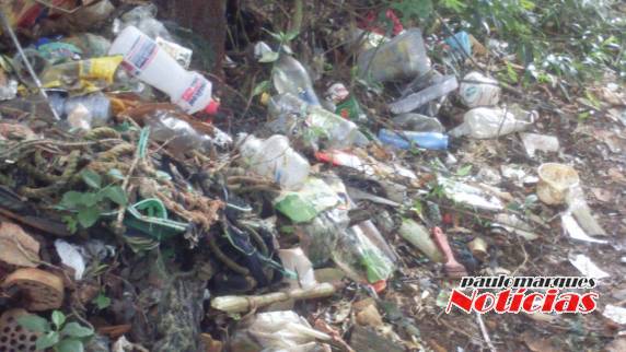 Pessoas descartam lixo próximo das moradias do bairro
