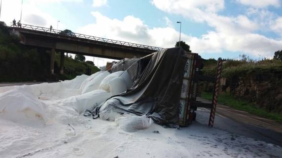 Veículo levava farinha, que ficou espalhada pela pista. Caminhoneiro foi levado ao hospital