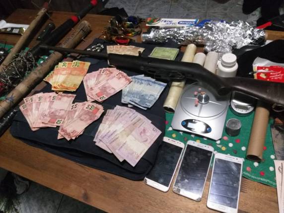 Polícia afirma que jovem apontou arma para policiais. Na casa onde ele estava, foram apreendidos drogas, munição, dinheiro, um colete balístico, entre outros objetos