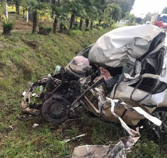 Veículo de passeio teve a dianteira amassada ao colidir contra um caminhão