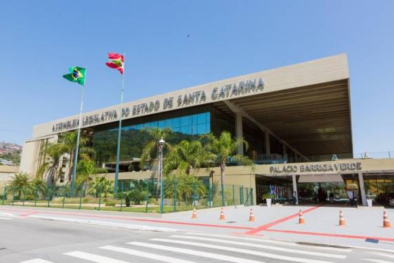 O projeto de lei foi apresentado pelo deputado estadual Ivan Naatz (PL), que se justifica dizendo que "o catarinense não sabe cantar o hino porque não se sente representado por ele"
