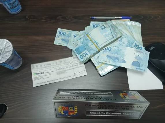 Votação para escolha da Mesa Diretora da Câmara de Mercês, na Zona da Mata, era transmitida ao vivo quando Marcelo Moto Som (Mobiliza) tirou pacotes de dinheiro no plenário. Presidente eleito vai assumir a Prefeitura devido à pendência judicial do prefeito eleito. Polícia investiga o caso.